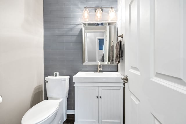 bathroom featuring toilet, tile walls, and vanity