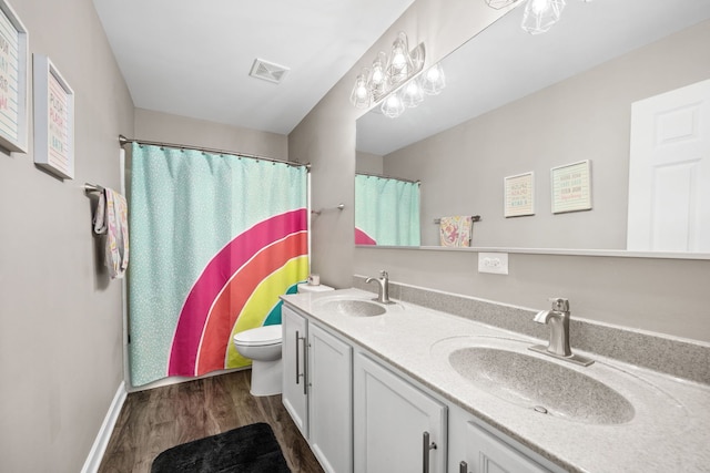 full bathroom featuring toilet, double vanity, a sink, and visible vents