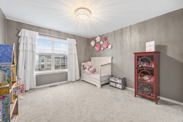 bedroom featuring a nursery area, baseboards, visible vents, and carpet flooring