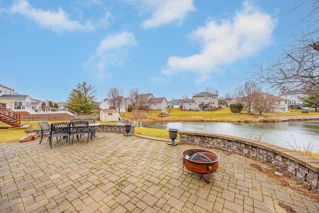 view of patio / terrace featuring a water view, an outdoor fire pit, and a residential view