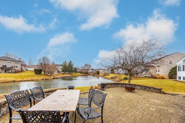 view of patio / terrace featuring a residential view, outdoor dining area, a water view, and a fire pit