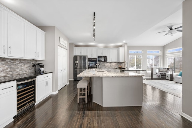 kitchen featuring dark wood finished floors, beverage cooler, a sink, and black appliances