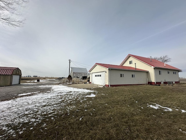 view of snow covered exterior featuring a yard and a garage