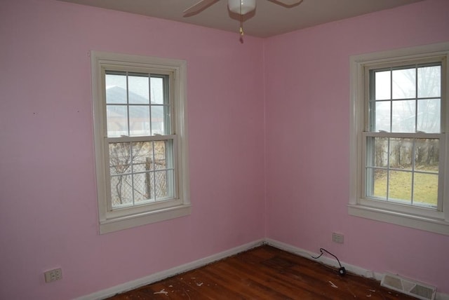 empty room with dark hardwood / wood-style flooring, ceiling fan, and a healthy amount of sunlight