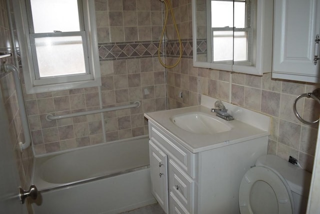 full bathroom with a healthy amount of sunlight, toilet, tile walls, and vanity