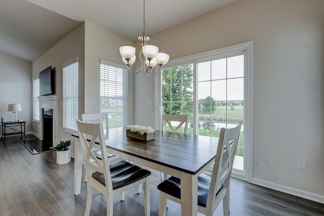 dining area featuring dark wood-type flooring, lofted ceiling, and a notable chandelier