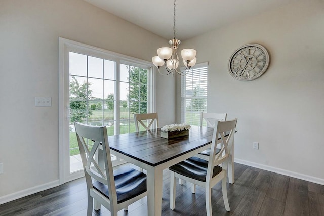 dining space with dark hardwood / wood-style flooring and an inviting chandelier