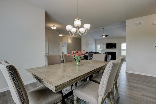 dining room with lofted ceiling, hardwood / wood-style floors, and ceiling fan with notable chandelier