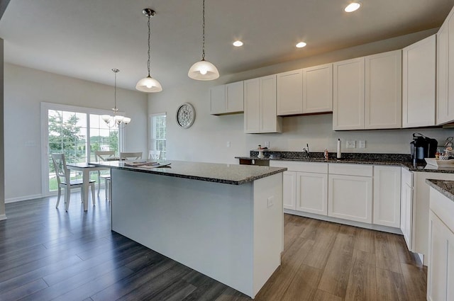 kitchen featuring white cabinetry, decorative light fixtures, a center island, and hardwood / wood-style floors