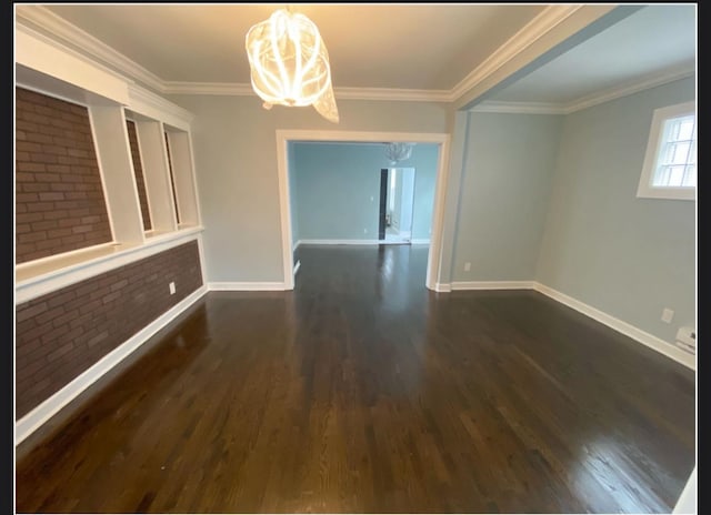 unfurnished dining area with a notable chandelier, ornamental molding, dark hardwood / wood-style floors, and brick wall