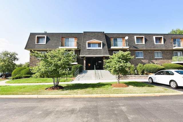 view of front of house featuring a balcony and a front lawn