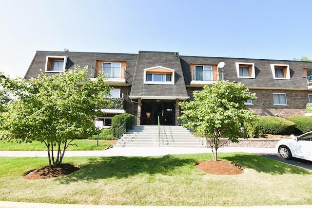 view of front of house with a balcony and a front lawn