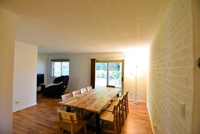 dining space with brick wall and light hardwood / wood-style flooring