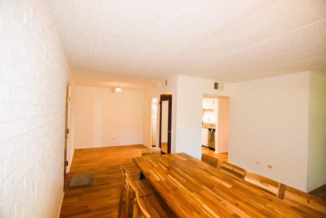 unfurnished room with hardwood / wood-style flooring and brick wall