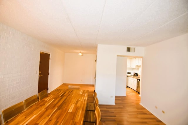 spare room featuring brick wall and hardwood / wood-style floors