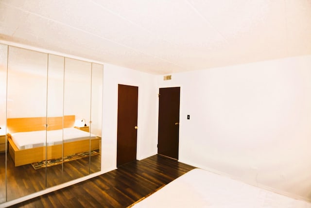 unfurnished bedroom featuring dark wood-type flooring and a closet