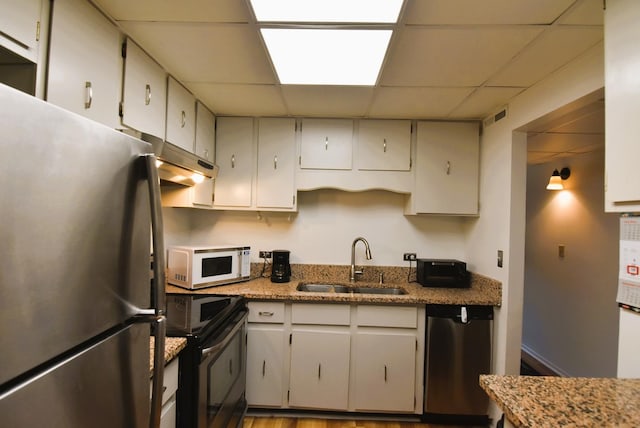 kitchen with stainless steel appliances, sink, white cabinets, and a drop ceiling