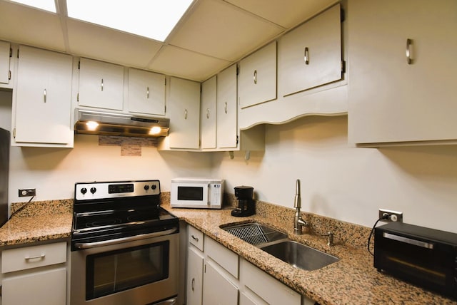 kitchen featuring a paneled ceiling, stainless steel electric stove, light stone countertops, and sink