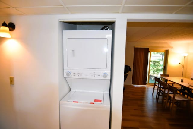 clothes washing area with dark wood-type flooring and stacked washer / dryer