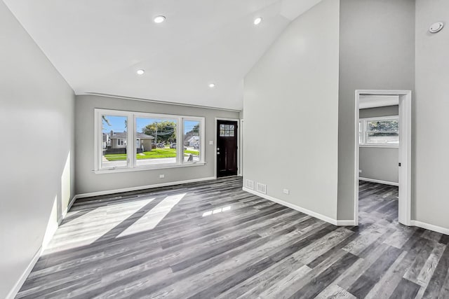 unfurnished living room featuring dark wood-type flooring and high vaulted ceiling