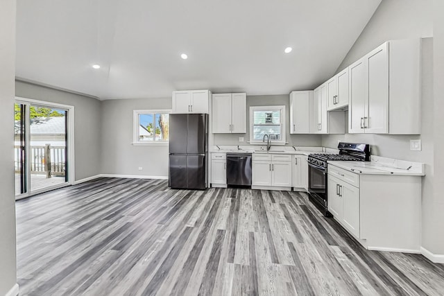 kitchen with white cabinets, black dishwasher, stainless steel fridge, and range with gas cooktop