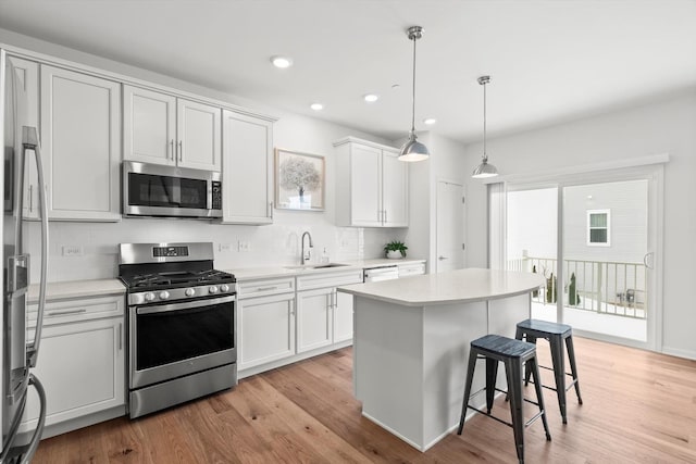 kitchen with sink, white cabinets, stainless steel appliances, and decorative light fixtures