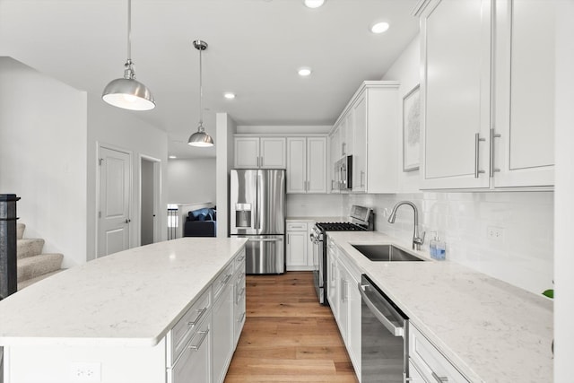 kitchen with a center island, light stone countertops, sink, appliances with stainless steel finishes, and white cabinets