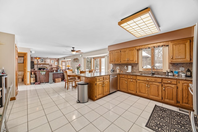 kitchen featuring sink, light tile patterned floors, tasteful backsplash, stainless steel dishwasher, and kitchen peninsula