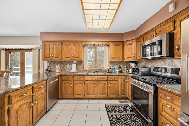 kitchen featuring sink, a wealth of natural light, stainless steel appliances, and dark stone counters