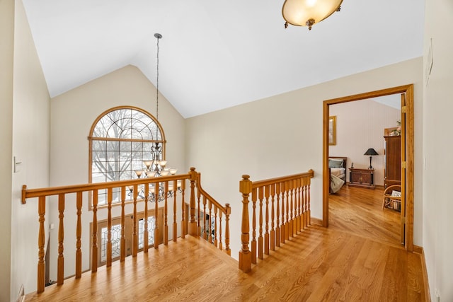 hallway featuring lofted ceiling, hardwood / wood-style floors, and a chandelier