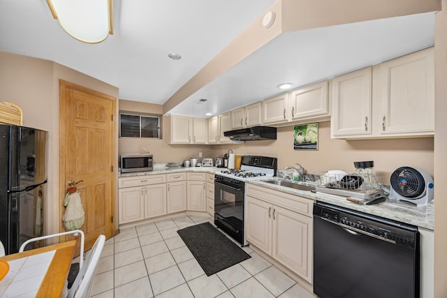 kitchen with sink, light tile patterned floors, tile counters, black appliances, and cream cabinetry