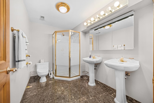 bathroom with toilet, a shower with shower door, and sink