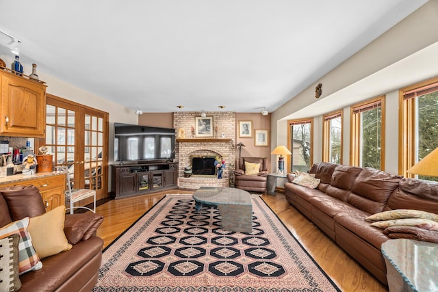 living room with hardwood / wood-style floors, french doors, and a brick fireplace