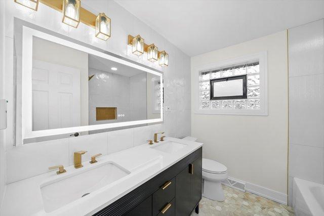 full bathroom featuring vanity, washtub / shower combination, and toilet