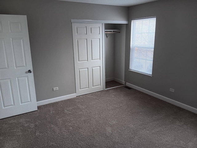 unfurnished bedroom featuring dark colored carpet and a closet