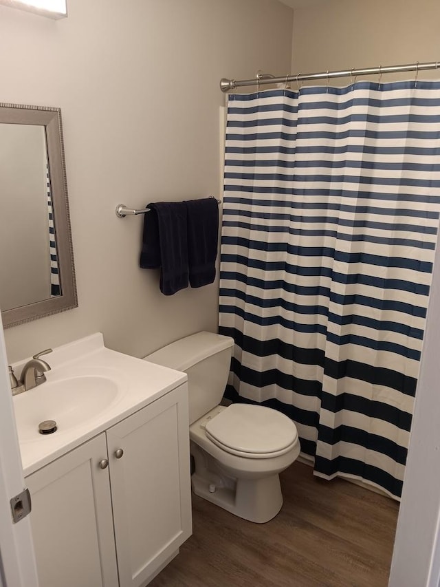 bathroom featuring vanity, wood-type flooring, toilet, and walk in shower