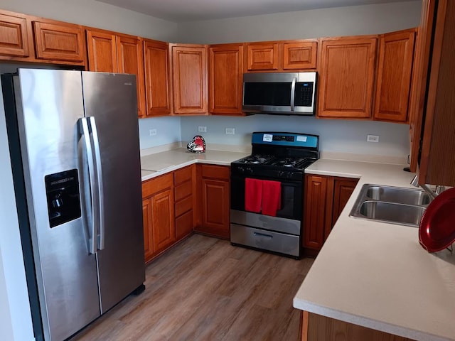 kitchen with stainless steel appliances, hardwood / wood-style flooring, and sink