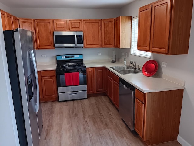 kitchen featuring appliances with stainless steel finishes, sink, and light wood-type flooring