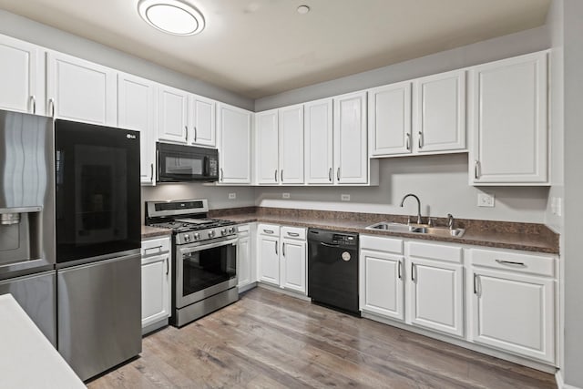 kitchen with white cabinetry, sink, light hardwood / wood-style flooring, and black appliances