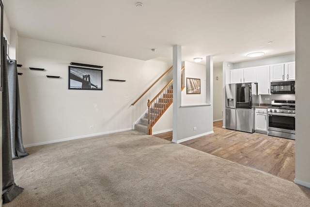 kitchen featuring light colored carpet, appliances with stainless steel finishes, and white cabinets