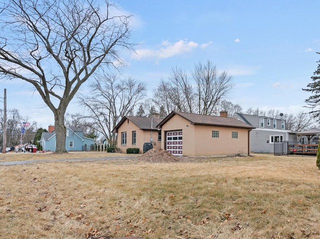 rear view of property with a yard, a chimney, and a detached garage