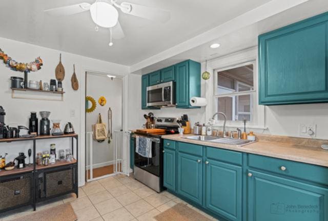 kitchen featuring light tile patterned floors, stainless steel appliances, light countertops, a sink, and ceiling fan