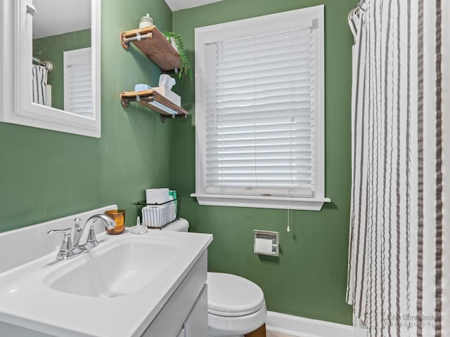 bathroom with toilet, baseboards, and vanity