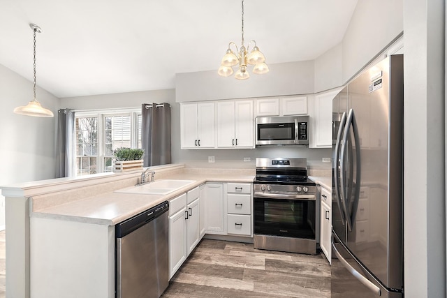 kitchen with stainless steel appliances, sink, hanging light fixtures, and white cabinets