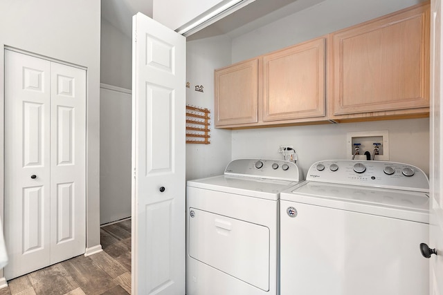 washroom featuring cabinets, washing machine and clothes dryer, and dark hardwood / wood-style flooring