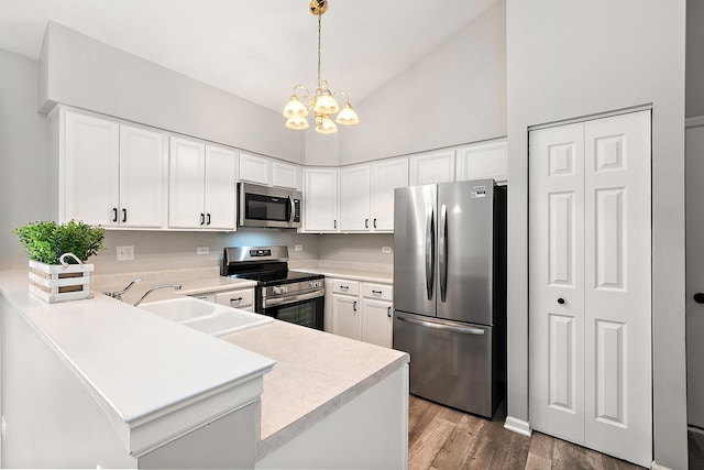 kitchen with sink, stainless steel appliances, white cabinets, decorative light fixtures, and kitchen peninsula