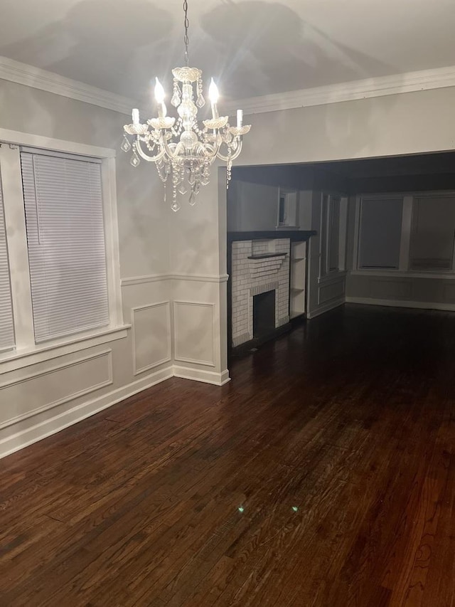 unfurnished living room featuring dark hardwood / wood-style flooring, crown molding, a chandelier, and a fireplace