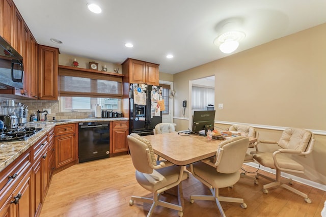 kitchen featuring light stone counters, decorative backsplash, light hardwood / wood-style flooring, and black appliances