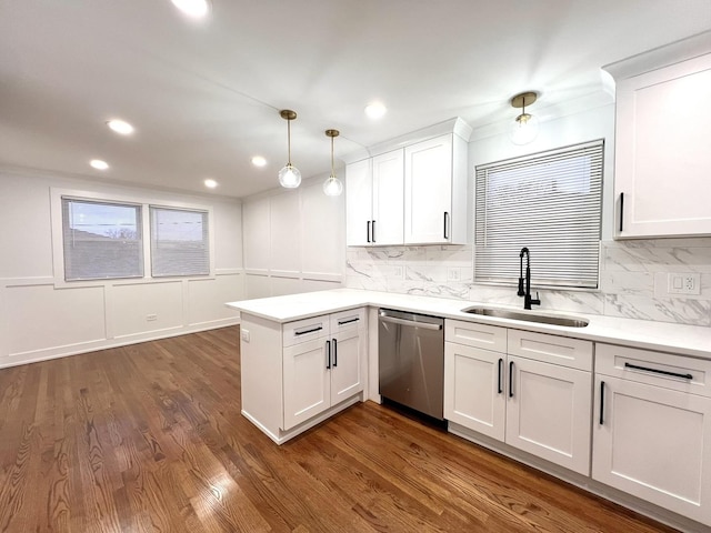 kitchen featuring pendant lighting, white cabinetry, sink, stainless steel dishwasher, and kitchen peninsula