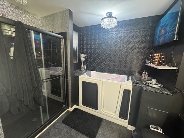 bathroom featuring an inviting chandelier and an enclosed shower